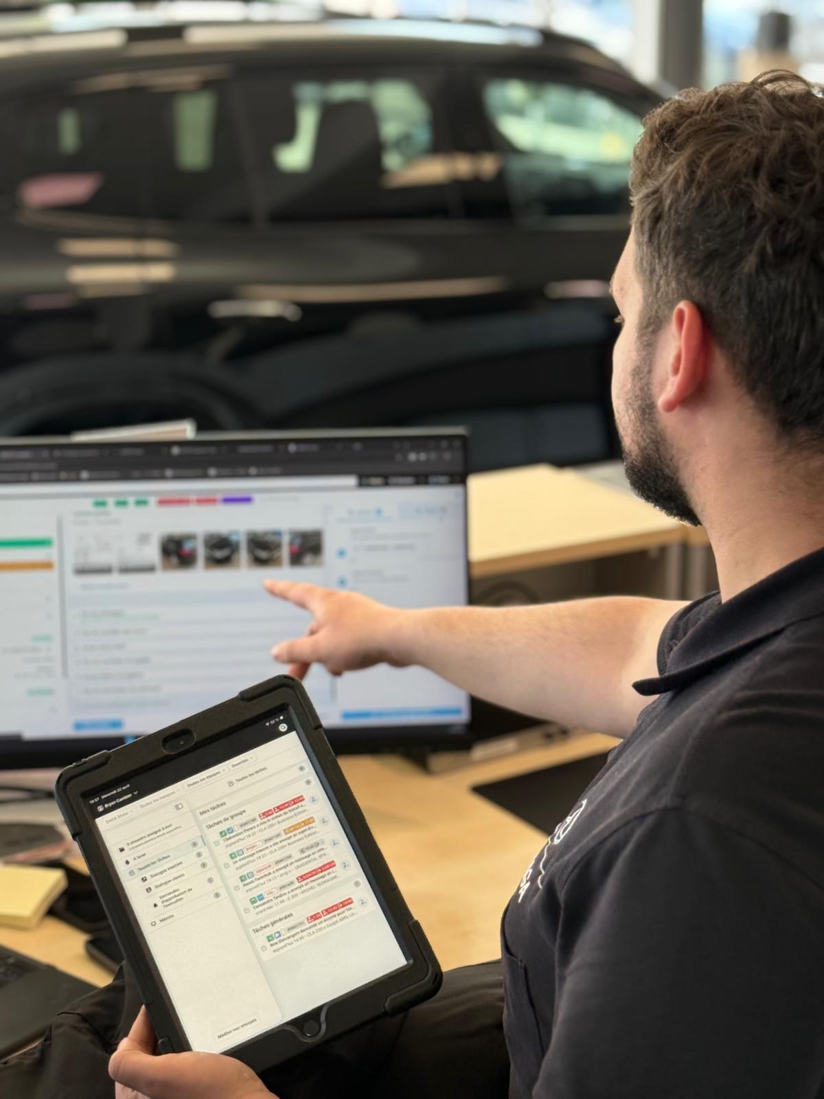 Advisor reviewing tasks on tablet and screen in the showroom, car in the background